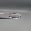 ​Studio close-up photographs displaying a 4.38-carat elongated oval-cut natural amethyst Katela gemstone held securely in precision tweezers against a neutral grey background.