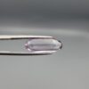 ​Studio close-up photographs displaying a 4.38-carat elongated oval-cut natural amethyst Katela gemstone held securely in precision tweezers against a neutral grey background.
