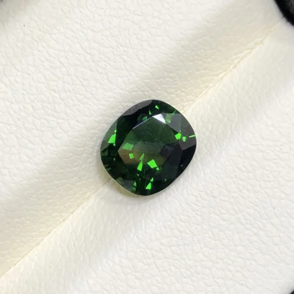 High-resolution scan of an official GGI (Galaxy Gemological Institute) Gemstone Report for a 1.48-carat Natural Chrome Green Tourmaline sourced from Tanzania, detailed with certificate number KHI2610280448, cushion mixed cut dimensions (7.77 x 6.94 x 4.33 mm), transparent green color, and QR verification code.