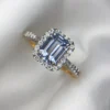 Close-up photograph of an 18K gold ring featuring a 1.53-carat emerald-cut pastel blue natural Ceylon sapphire centerpiece surrounded by a shimmering halo of 0.33-carat natural diamond accents against a soft white fabric background.