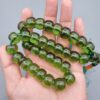 Studio close-up photograph of a 98-gram olive-green German Bakelite Sandaloos tasbih rosary, featuring barrel-cut polished beads, an intricately sculpted imam bead, and a rich green tassel against a light background.