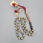 Studio close-up photograph of a 39-gram natural Yusr coral retro swirl striped composite tasbih prayer bead strand, featuring barrel-cut beads with turquoise-blue, maroon, and cream accents, a matching imam bead, and a multi-colored tassel against a light grey background.