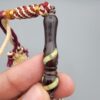Studio close-up photograph of a 39-gram natural Yusr coral retro swirl striped composite tasbih prayer bead strand, featuring barrel-cut beads with turquoise-blue, maroon, and cream accents, a matching imam bead, and a multi-colored tassel against a light grey background.