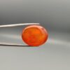 ​Studio close-up photographs displaying a 35.21-carat oval-cut natural nebula glow carnelian agate gemstone featuring unique white crystalline plumes, held securely in precision tweezers against a neutral background.