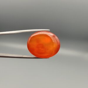 ​Studio close-up photographs displaying a 35.21-carat oval-cut natural nebula glow carnelian agate gemstone featuring unique white crystalline plumes, held securely in precision tweezers against a neutral background.