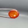 ​Studio close-up photographs displaying a 35.21-carat oval-cut natural nebula glow carnelian agate gemstone featuring unique white crystalline plumes, held securely in precision tweezers against a neutral background.