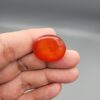 ​Studio close-up photographs displaying a 35.21-carat oval-cut natural nebula glow carnelian agate gemstone featuring unique white crystalline plumes, held securely in precision tweezers against a neutral background.