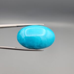 Two-part macro photograph of a 46.42-carat natural blue Sleeping Beauty turquoise (Razaki Feroza) oval cabochon held in tweezers, featuring a high-gloss, flawless sky-blue front face and a reverse side displaying a pale fibrous host matrix.