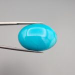 Multi-angle macro photographs of a 32-carat natural vibrant sky-blue Sleeping Beauty turquoise (Razaki Feroza) oval cabochon held in tweezers, featuring a smooth domed front face with subtle natural variations and a reverse side displaying an authentic dark matrix.