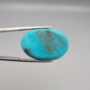 Multi-angle macro photographs of a 32-carat natural vibrant sky-blue Sleeping Beauty turquoise (Razaki Feroza) oval cabochon held in tweezers, featuring a smooth domed front face with subtle natural variations and a reverse side displaying an authentic dark matrix.