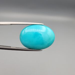 Multi-angle macro photographs of a 12.89-carat natural vibrant sky-blue Sleeping Beauty turquoise (Razaki Feroza) oval cabochon held in tweezers, featuring a brilliant polished front face and a reverse surface displaying an intricate greenish-grey and white host matrix.