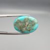 Multi-angle macro photographs of a 12.89-carat natural vibrant sky-blue Sleeping Beauty turquoise (Razaki Feroza) oval cabochon held in tweezers, featuring a brilliant polished front face and a reverse surface displaying an intricate greenish-grey and white host matrix.