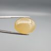Multi-angle macro photographs of a 27.91-carat natural yellow chalcedony agate (Zard Aqeeq) oval cabochon from Iran held in metal tweezers, showcasing a smooth, domed profile, uniform honey-yellow translucency, and a high-gloss reflective surface.