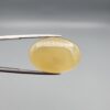 Multi-angle macro photographs of a 27.49-carat natural yellow chalcedony agate (Zard Aqeeq) oval cabochon from Iran held in metal tweezers, showcasing a smooth, domed profile, uniform honey-yellow translucency, and a high-gloss reflective surface.