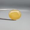 Multi-angle macro photographs of a 35.41-carat natural yellow chalcedony agate (Zard Aqeeq) oval cabochon from Iran held in metal tweezers, showcasing a smooth, domed profile, uniform honey-yellow translucency, and a high-gloss reflective surface.
