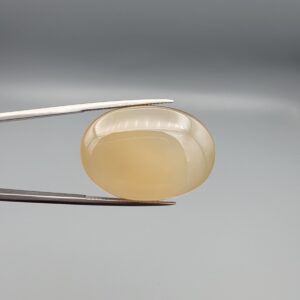 Multi-angle macro photographs of a 41.75-carat natural yellow chalcedony agate (Zard Aqeeq) oval cabochon from Iran held in metal tweezers, showcasing a smooth, domed profile, uniform honey-yellow translucency, and a high-gloss reflective surface.