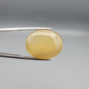 Multi-angle macro photographs of a 26.29-carat natural yellow chalcedony agate (Zard Aqeeq) oval cabochon from Iran held in metal tweezers, showcasing a smooth, domed profile, uniform honey-yellow translucency, and a high-gloss reflective surface.