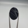 Multi-angle macro photographs of a 26.54-carat natural black banded agate (Sulemani Aqeeq) oval cabochon held vertically in metal tweezers, displaying a mirror-polished deep obsidian black surface accented by sharp V-shaped geometric chevron lines and fine parallel fortification banding.