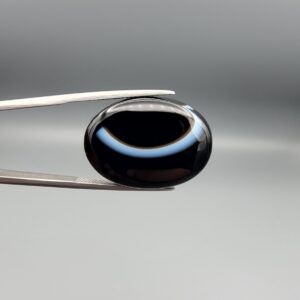 Exceptional 26.53 carat natural black banded agate (Sulemani Aqeeq), expertly finished into a high-gloss oval cabochon displaying a bold, curved concentric white band wrapping seamlessly around an intense jet-black core.