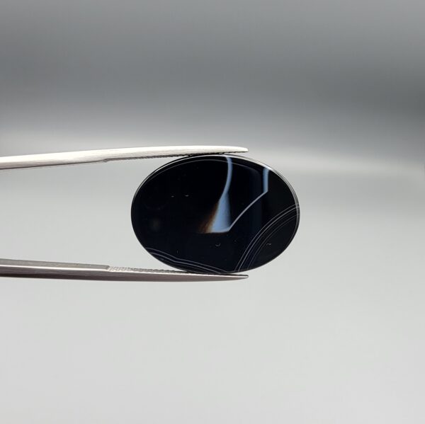 Striking 25.19 carat natural black banded agate (Sulemani Aqeeq) featuring a mirror-polished finish and clean, architecturally precise angular white banding lines contrasting against an intense jet-black body.