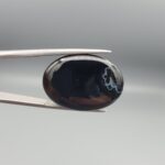 Rare 26.92 carat natural black banded agate (Sulemani Aqeeq) featuring a mirror-polished deep black body adorned with an intriguing cluster of rounded cellular white eye formations near the rim.