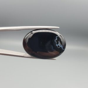 Rare 26.92 carat natural black banded agate (Sulemani Aqeeq) featuring a mirror-polished deep black body adorned with an intriguing cluster of rounded cellular white eye formations near the rim.