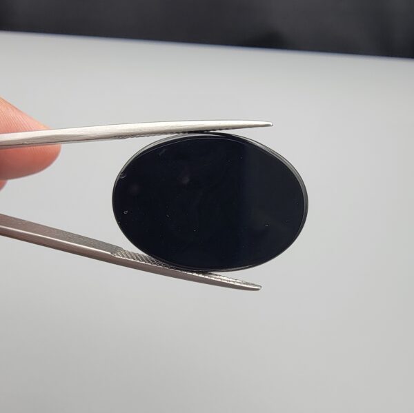 Rare 26.66 carat natural black banded agate (Sulemani Aqeeq) featuring a mirror-polished deep black body traversed by an extraordinary, luminous blue-gray and bright white eye-like arc.