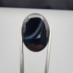 Rare 26.66 carat natural black banded agate (Sulemani Aqeeq) featuring a mirror-polished deep black body traversed by an extraordinary, luminous blue-gray and bright white eye-like arc.