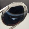 Rare 26.66 carat natural black banded agate (Sulemani Aqeeq) featuring a mirror-polished deep black body traversed by an extraordinary, luminous blue-gray and bright white eye-like arc.
