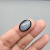 Rare 9.70 carat natural black banded agate (Sulemani Aqeeq), expertly finished into a high-gloss oval cabochon displaying a rich black rim encapsulating a translucent, luminous blue-grey crystalline matrix center.