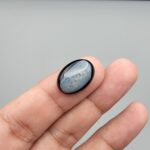Rare 9.70 carat natural black banded agate (Sulemani Aqeeq), expertly finished into a high-gloss oval cabochon displaying a rich black rim encapsulating a translucent, luminous blue-grey crystalline matrix center.