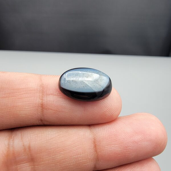Rare 9.70 carat natural black banded agate (Sulemani Aqeeq), expertly finished into a high-gloss oval cabochon displaying a rich black rim encapsulating a translucent, luminous blue-grey crystalline matrix center.