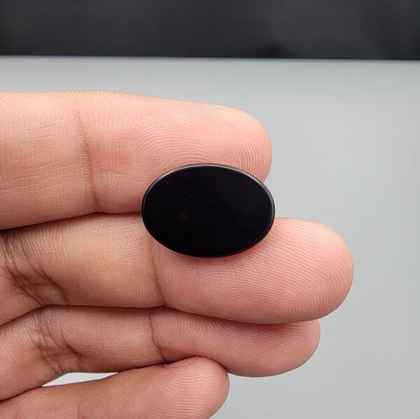 Rare 9.70 carat natural black banded agate (Sulemani Aqeeq), expertly finished into a high-gloss oval cabochon displaying a rich black rim encapsulating a translucent, luminous blue-grey crystalline matrix center.