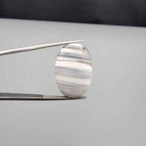 Multi-angle macro photographs of an 18.37-carat natural banded agate (Sulemani Aqeeq) oval cabochon held in metal tweezers, showcasing a smooth, high-gloss surface, translucent monochrome grey-and-white horizontal banding, and fine natural mineral strata.