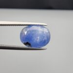 Multi-angle macro photographs of a 7.07-carat natural blue sapphire (Neelam) oval gemstone from Sri Lanka held in metal tweezers, showcasing precision oval faceting, a cornflower blue body, natural internal texturing, and dark mineral inclusions.