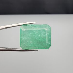 High-resolution digital scan of an official Galaxy Gemological Institute (GGI) Gemstone Report certificate (No. KHI2610700414) dated 14 October 2026 for a massive 19.56-carat semi-transparent green natural Emerald (Beryl) featuring an emerald step cut with moderate oiling.