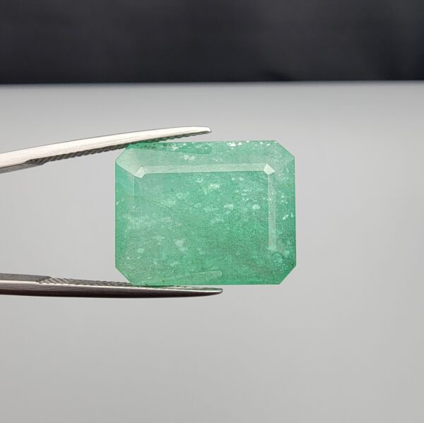 High-resolution digital scan of an official Galaxy Gemological Institute (GGI) Gemstone Report certificate (No. KHI2610700414) dated 14 October 2026 for a massive 19.56-carat semi-transparent green natural Emerald (Beryl) featuring an emerald step cut with moderate oiling.