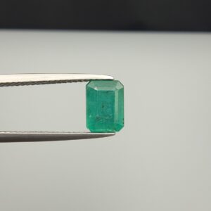 Multi-angle macro photographs of a 2.04-carat natural Zambian emerald (Zamrud) held in metal tweezers, displaying a classic emerald-cut octagonal shape, vibrant leafy green color, and characteristic natural internal inclusions (jardin) throughout the crystal structure.