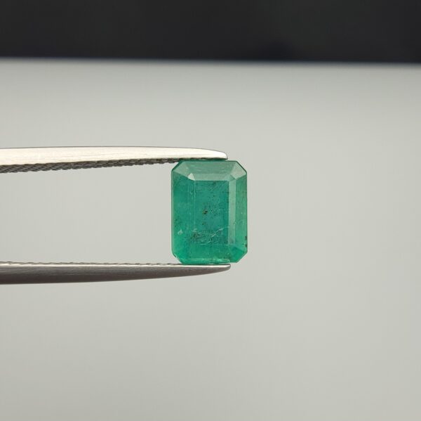 Multi-angle macro photographs of a 2.04-carat natural Zambian emerald (Zamrud) held in metal tweezers, displaying a classic emerald-cut octagonal shape, vibrant leafy green color, and characteristic natural internal inclusions (jardin) throughout the crystal structure.
