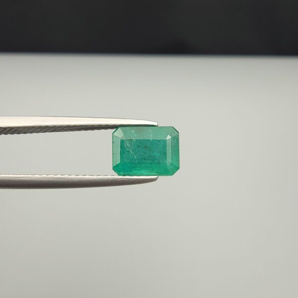 Multi-angle macro photographs of a 2.04-carat natural Zambian emerald (Zamrud) held in metal tweezers, displaying a classic emerald-cut octagonal shape, vibrant leafy green color, and characteristic natural internal inclusions (jardin) throughout the crystal structure.
