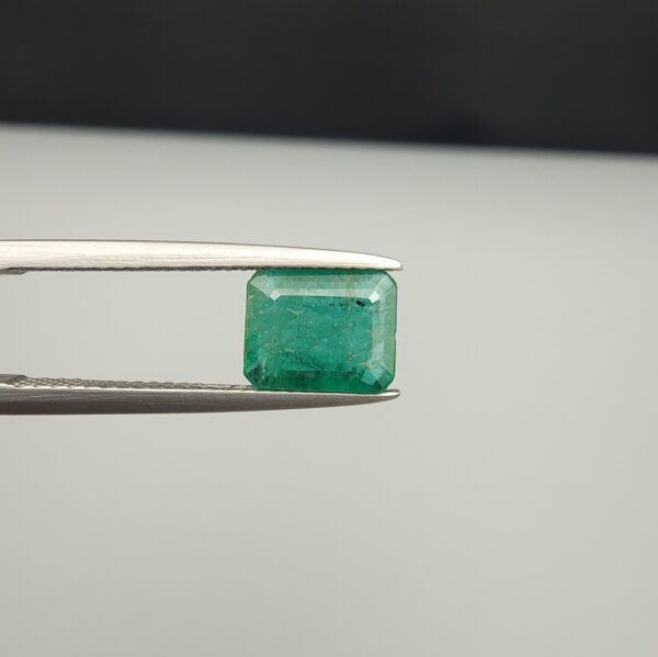 Multi-angle macro photographs of a 1.86-carat natural Zambian emerald (Zamrud) held in metal tweezers, showcasing a classic step-cut emerald octagonal shape, vibrant leafy green hue, and characteristic natural internal inclusions (jardin) across the table.