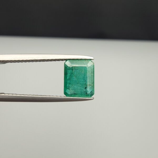 Multi-angle macro photographs of a 1.86-carat natural Zambian emerald (Zamrud) held in metal tweezers, showcasing a classic step-cut emerald octagonal shape, vibrant leafy green hue, and characteristic natural internal inclusions (jardin) across the table.
