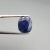 Multi-angle macro photographs of a massive 10.33-carat natural unheated Afghan blue indigo sapphire (Neelam) held in gem tweezers, showcasing a faceted oval cut, deep rich indigo blue hue, and silk inclusion pattern.