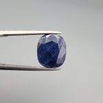 Multi-angle macro photographs of a massive 10.33-carat natural unheated Afghan blue indigo sapphire (Neelam) held in gem tweezers, showcasing a faceted oval cut, deep rich indigo blue hue, and silk inclusion pattern.