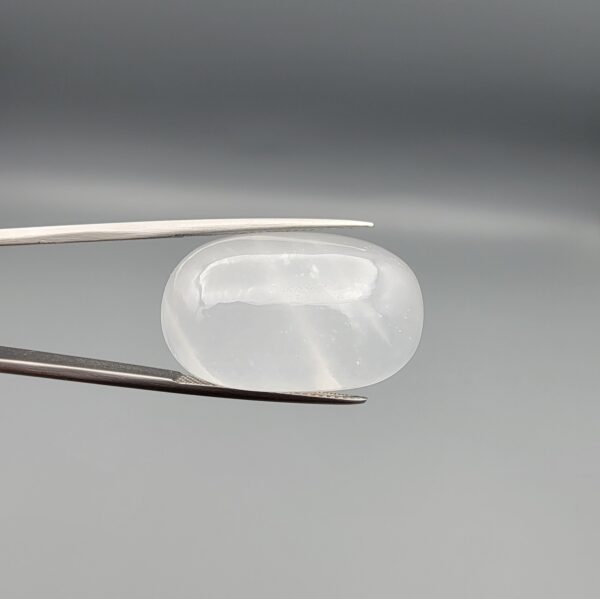 Multi-angle macro photographs showing a massive 41.67-carat natural Durr-e-Najaf (Clear Rock Crystal Quartz) cabochon held in metal tweezers and displayed on fingertips, showcasing an elongated smooth oval dome, water-clear transparency, and subtle organic internal veil growth.