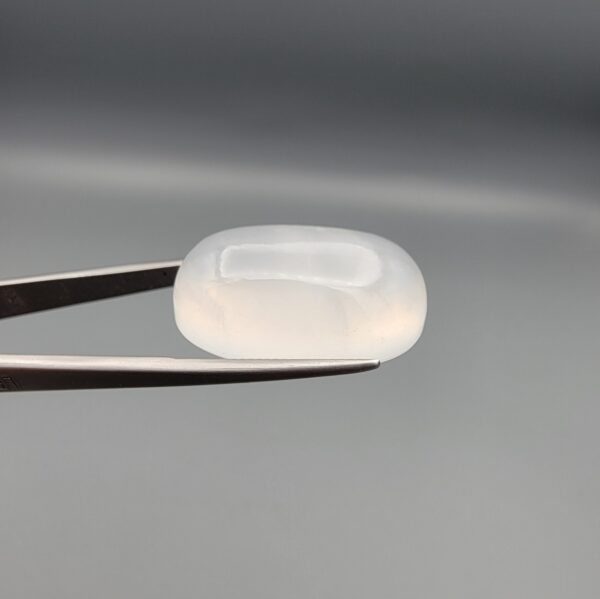 Multi-angle macro photographs showing a massive 41.67-carat natural Durr-e-Najaf (Clear Rock Crystal Quartz) cabochon held in metal tweezers and displayed on fingertips, showcasing an elongated smooth oval dome, water-clear transparency, and subtle organic internal veil growth.