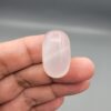 Multi-angle macro photographs showing a massive 41.67-carat natural Durr-e-Najaf (Clear Rock Crystal Quartz) cabochon held in metal tweezers and displayed on fingertips, showcasing an elongated smooth oval dome, water-clear transparency, and subtle organic internal veil growth.