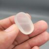 Multi-angle macro photographs showing a massive 41.67-carat natural Durr-e-Najaf (Clear Rock Crystal Quartz) cabochon held in metal tweezers and displayed on fingertips, showcasing an elongated smooth oval dome, water-clear transparency, and subtle organic internal veil growth.