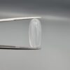 Multi-angle macro photographs of a 9.56-carat natural Durr-e-Najaf (Clear Rock Crystal Quartz) cabochon held vertically in stainless steel gem tweezers and resting on fingers, displaying an elegant slender elongated oval dome, water-clear transparency, and subtle organic internal veil growth.
