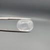 Macro photograph of an 11.36-carat natural Durr-e-Najaf (Clear Rock Crystal Quartz) cabochon held horizontally in stainless steel gem tweezers against a neutral grey background, displaying a smooth oval dome, water-clear transparency, and subtle organic internal veil inclusions.